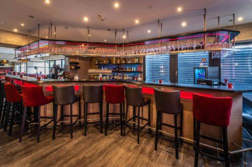 a bar with red bar stools in a restaurant at PLAZA INN Heilbronn in Heilbronn