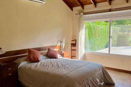 a bedroom with a bed and a large window at Casa en Ing. Maschwitz con gran parque y pileta in Ingeniero Maschwitz