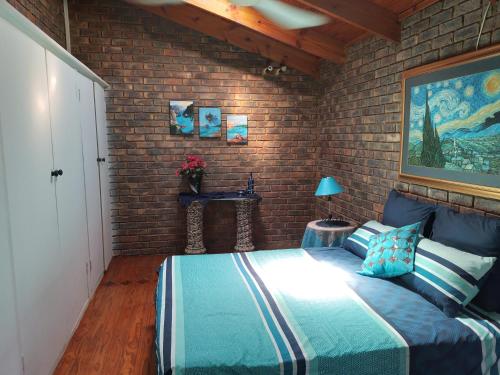 a bedroom with a bed and a brick wall at Sharon's Dream - Self Catering Apartment in Hartbeespoort