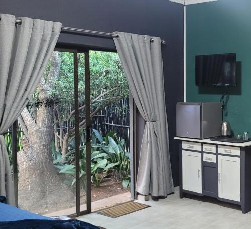 Schlafzimmer mit einer Glasschiebetür und einem TV in der Unterkunft Pandora's Guest Lodge in Klerksdorp