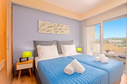 a bedroom with a blue bed with towels on it at Villa Petra Gouvia by Villa Plus in Gouvia
