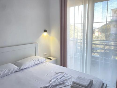 een wit bed in een slaapkamer met een groot raam bij Villa Denis Ksamil in Ksamil