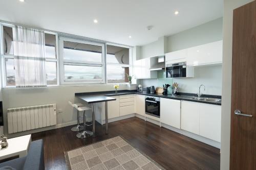eine Küche mit weißen Schränken und einer schwarzen Arbeitsplatte in der Unterkunft Superb Studio in London