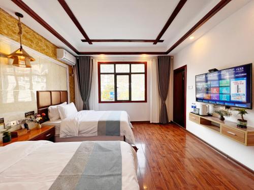 a hotel room with two beds and a flat screen tv at Yijingju Humanistic Inn in Zhangjiajie