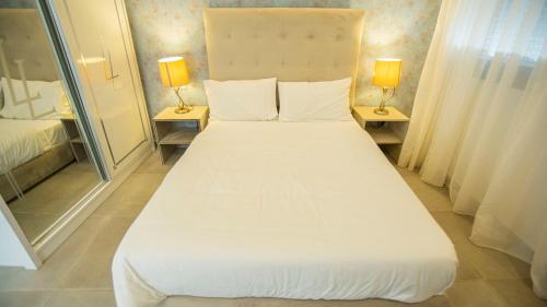 a large white bed in a room with two lamps at Villa Sahara Line in Dakhla
