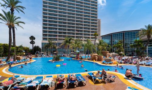 una piscina en un complejo con gente sentada en sillas en Medplaya Hotel Flamingo Oasis, en Benidorm