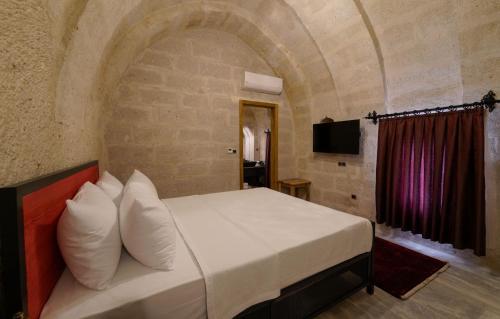 a bedroom with a bed in a stone wall at The Niche Cave Hotel in Goreme