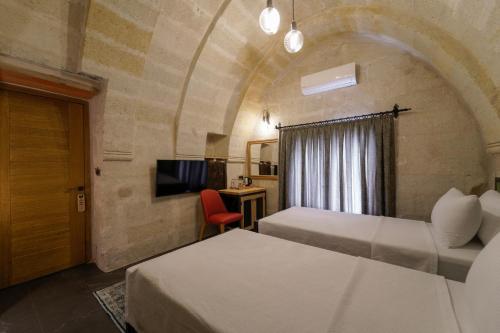 a hotel room with two beds and a tv at The Niche Cave Hotel in Goreme