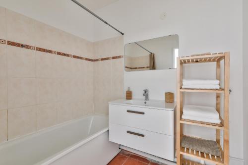 La salle de bains est pourvue d'un lavabo, d'un miroir et d'une baignoire. dans l'établissement 123home-Le park side, à Chessy
