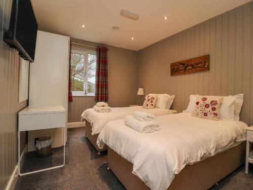 two twin beds in a room with a tv at Holly Lodge in Preston
