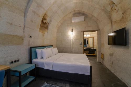 a bedroom with a bed in a stone wall at The Niche Cave Hotel in Goreme