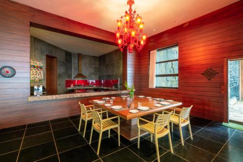 a dining room with a table and chairs and a chandelier at amã Stays & Trails Kailash House in Kodaikānāl
