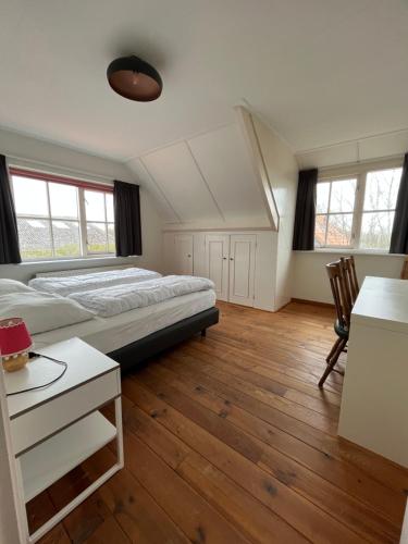 um quarto com uma cama, uma secretária e 2 janelas em Het Landhuis em Oostkapelle