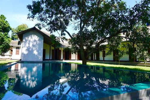 una piscina frente a una casa con un árbol en Stuart House Tangalle, en Tangalle