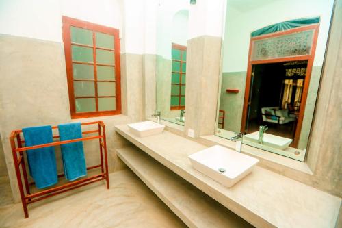 a bathroom with two sinks and two mirrors at Stuart House Tangalle in Tangalle