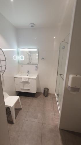 a white bathroom with a sink and a shower at Logis Hôtel du Fer à Cheval in Yenne