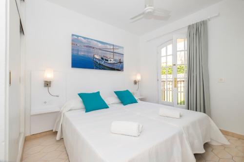 a white bedroom with a large bed with blue pillows at Girasols Gardens Sup in Son Bou