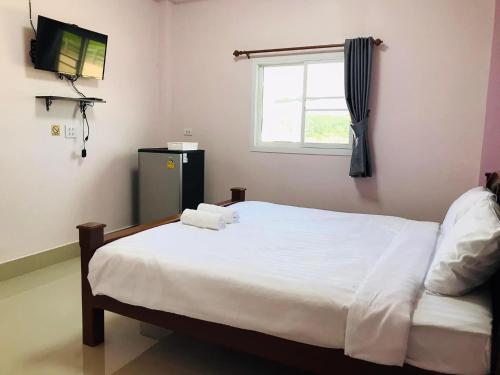 een slaapkamer met een wit bed en een raam bij โรงแรม เทวาแกรนด์ รีสอร์ท กุฉินารายณ์ กาฬสินธุ์ in Ban Na Ko