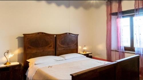 1 dormitorio con 1 cama con cabecero de madera y ventana en Agriturismo San Rocco Verucchio, en Verucchio