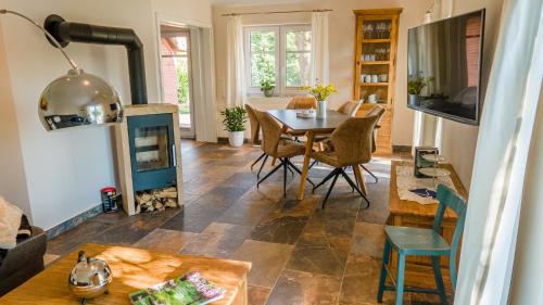 een woonkamer met een tafel en een open haard bij Reetdach Ostfriesenhaus in Südbrookmerland