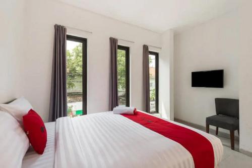 a bedroom with a bed and a chair and windows at RedDoorz near Kaza Mall Surabaya in Plosobegem