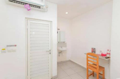 um quarto com uma casa de banho com uma porta e uma cadeira em RedDoorz near Kaza Mall Surabaya em Plosobegem