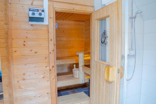 uma sauna de madeira com um chuveiro num quarto em Reetdach Ostfriesenhaus em Südbrookmerland