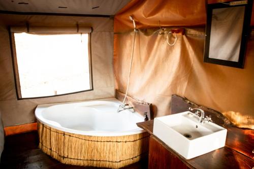 y baño con bañera y lavamanos. en Nhoma Safari Camp, en Tsumkwe