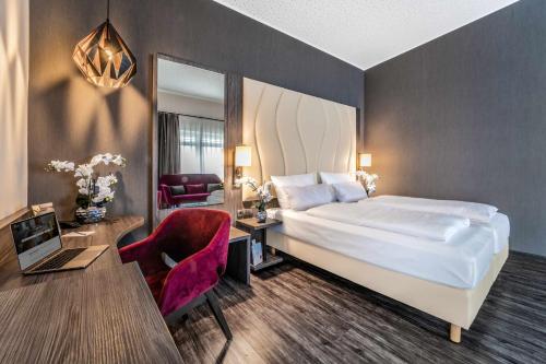 a hotel room with a bed and a desk and a chair at PLAZA INN Heilbronn in Heilbronn