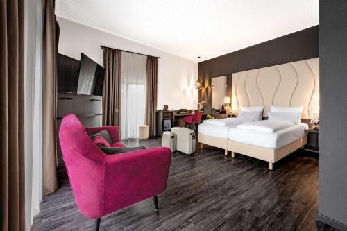 a hotel room with a bed and a pink chair at Best Western Hotel am Kastell in Heilbronn