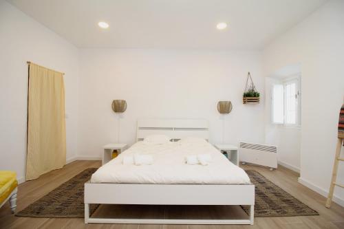 Un dormitorio blanco con una gran cama blanca. en Terraço do Castelo, en Arraiolos