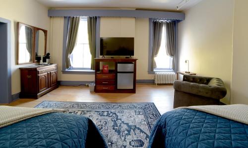 a bedroom with two beds and a television and a chair at Oneida Community Mansion House in Oneida