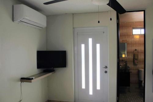 a room with a door with a tv on the wall at Marilou Apt A in Levittown