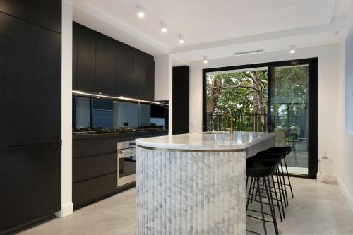 a kitchen with black cabinets and a bar with stools at Luxury Waterside Home Sanctuary in Sydney