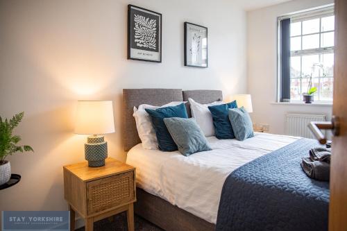 a bedroom with a large bed with blue pillows at Stay Yorkshire Hamilton Mews Apartment in Doncaster