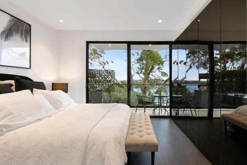 um quarto com uma grande cama branca e uma varanda em Luxury Waterside Home Sanctuary em Sydney