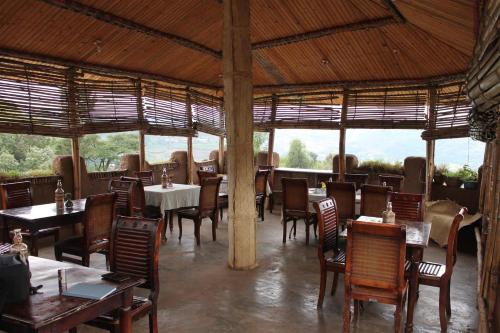 a restaurant with wooden tables and chairs and windows at Lodge Du Chateau in Gonder
