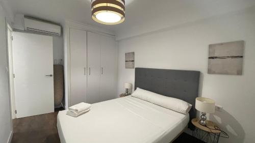 een slaapkamer met een wit bed en een lamp bij apartamento con vista al mar in Benalmádena