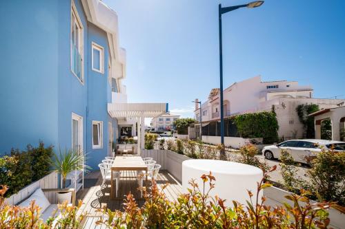 a balcony with white chairs and a blue building at Casa Azul Sagres - Rooms & Apartments in Sagres