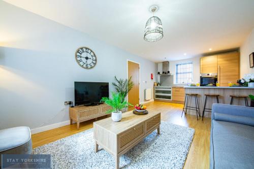 a living room with a clock on the wall at Stay Yorkshire Hamilton Mews Apartment in Doncaster
