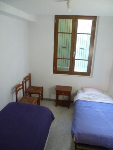 une chambre avec deux lits et une fenêtre et une chaise dans l'établissement Une vue sur la Baume, à Sisteron