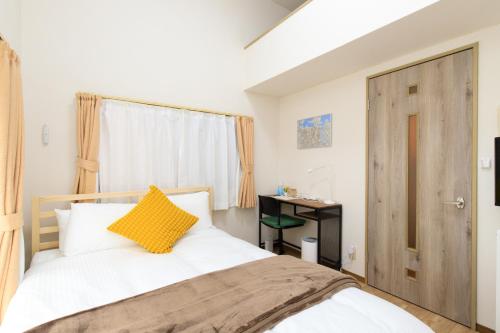 Un dormitorio con una cama blanca con una almohada amarilla. en Rooms天神 02, en Fukuoka