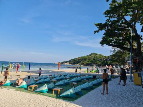 - une plage avec des chaises bleues et des personnes sur la plage dans l'établissement Almost Famous Hostel, à Haad Rin