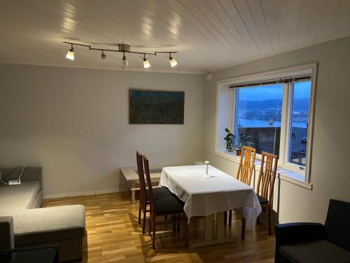 a dining room with a table and chairs and a window at Panorama Apartment Damsgård in Bergen