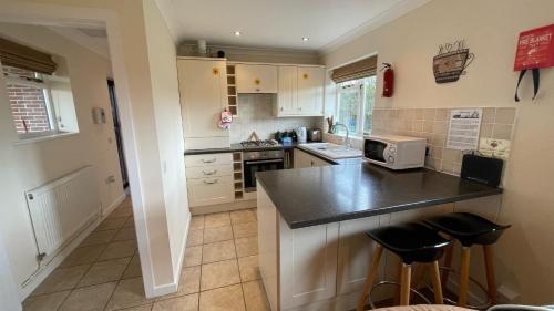 a kitchen with white cabinets and a black counter top at Swallows Retreat in Fordingbridge