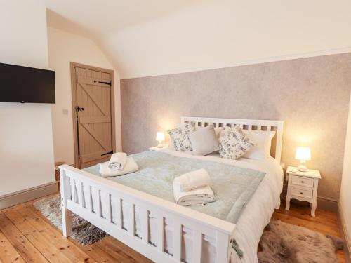 a bedroom with a white bed with two pillows at Holly Barn in Hull
