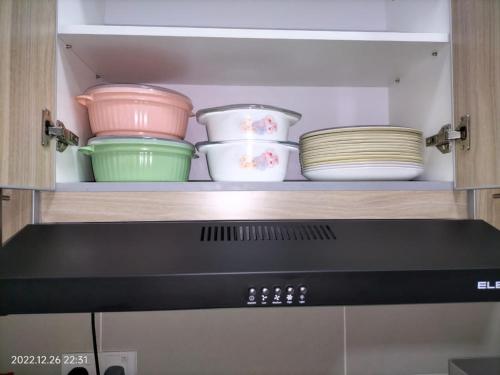 a shelf with bowls and plates on top of a microwave at Damai Homestay Almyra in Kajang