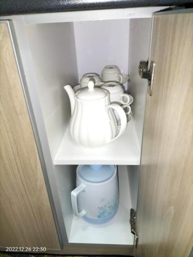 a cupboard with a tea pot and cups on it at Damai Homestay Almyra in Kajang