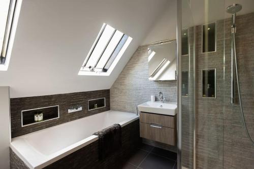 a bathroom with a tub and a sink and a shower at The Old Stables, Derrydown Farm in Andover