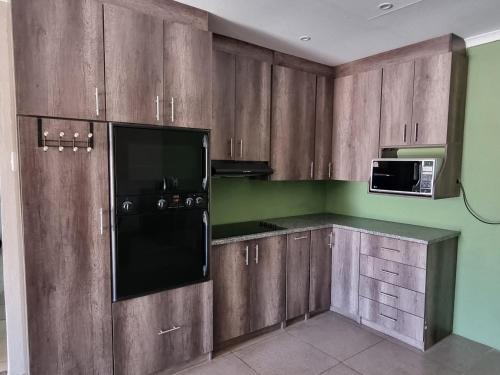 a kitchen with wooden cabinets and a microwave at Pro Plants Accommodation in Kimberley